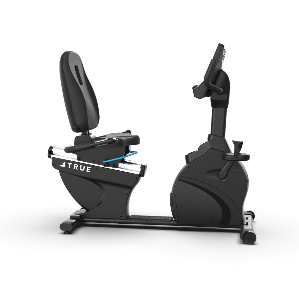 A black recumbent exercise bike with a large seat, backrest, digital display screen, and pedal system, viewed from the side on a white background. The brand name TRUE is visible on the side.